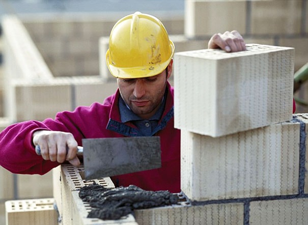кладет кирпич рабочий